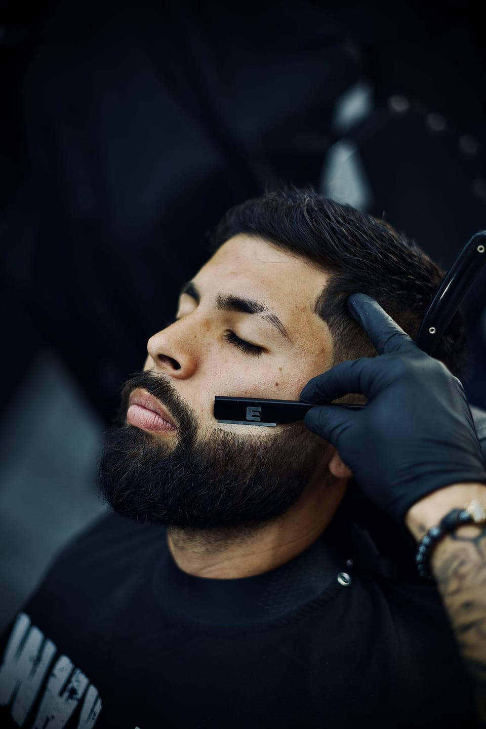 Barbero de Why Not Eixample arreglando una barba con navaja